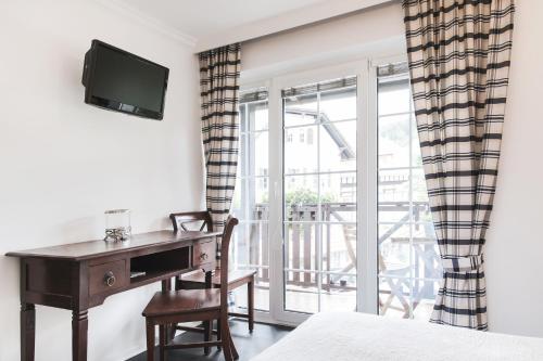 a bedroom with a desk and a bed and a window at Strandhotel Sille in Reifnitz