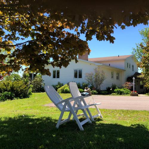 two white chairs sitting in the grass in front of a house at Fair Isle Motel in Charlottetown