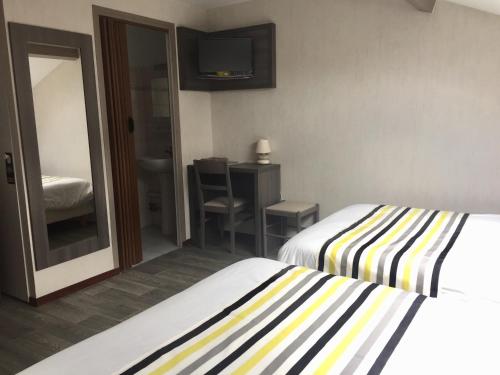 a hotel room with two beds and a mirror at Hôtel de L'Avenue in Tarbes