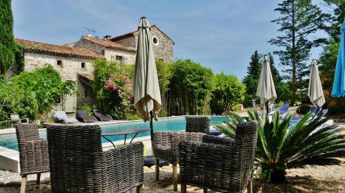 a patio with chairs and an umbrella and a pool at Mas Escombelle in Barjac