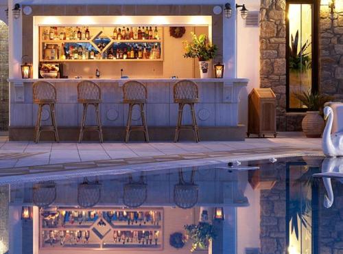 a bar with chairs in front of a swimming pool at Grand Beach Hotel in Mýkonos City