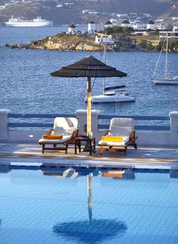 a swimming pool with two chairs and an umbrella at Grand Beach Hotel in Mýkonos City
