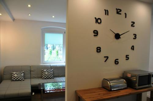 a living room with a clock on the wall at Apartamenty Centrum Słupsk in Słupsk