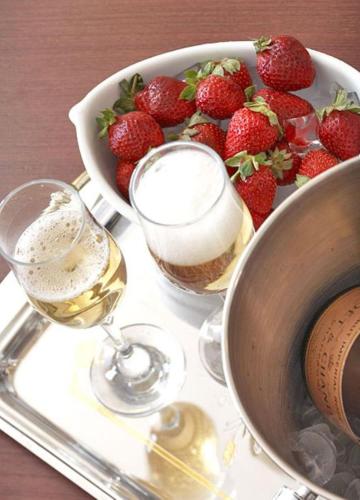 a tray with a bowl of strawberries and a glass of wine at Grand Beach Hotel in Mýkonos City
