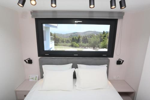 a bedroom with a large window above a bed at Blue Avenue in Paliouri