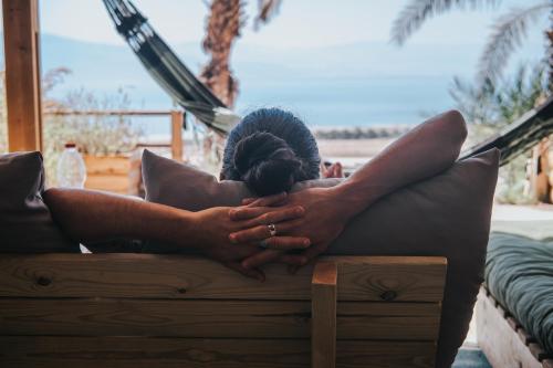 a woman laying on a couch with her head on a pillow at Ein Gedi Camp Lodge in Ein Gedi