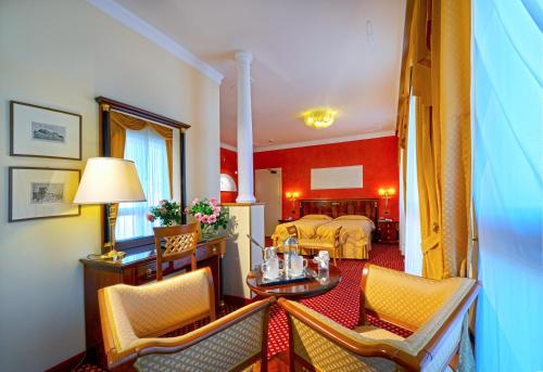 アーバノ・テルメにあるHotel Aurora Termeのベッド、テーブル、椅子が備わるホテルルームです。