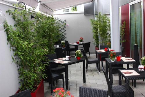 a restaurant patio with tables and chairs and plants at Expo Hotel Milan in Parabiago