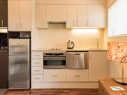 a kitchen with white cabinets and stainless steel appliances at Sea Spray Suites in Paihia