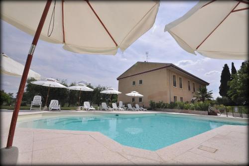 uma piscina com guarda-sóis e cadeiras e um edifício em Agriturismo Panorama em Castelnuovo del Garda
