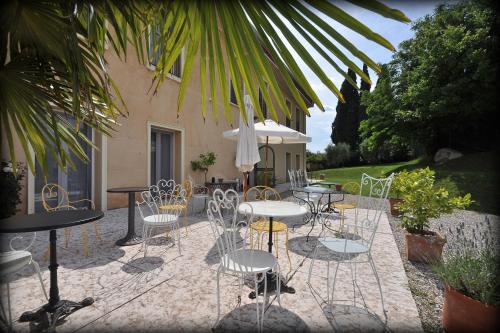un patio con sillas, mesas y una sombrilla en Agriturismo Panorama, en Castelnuovo del Garda