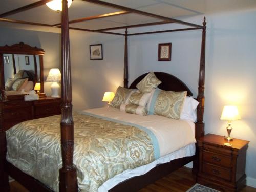 een slaapkamer met een hemelbed en een spiegel bij Abide Within Bed & Breakfast in Truro