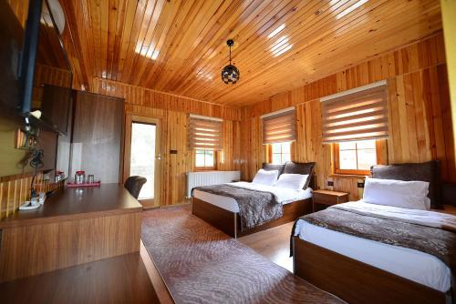 a bedroom with two beds in a wooden room at Goblec Hotel & Bungalow in Uzungol