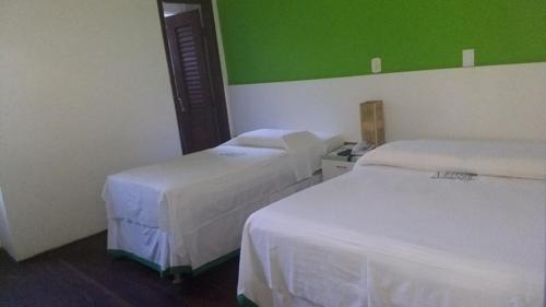 a room with two beds and a green wall at Pousada Maramazon in São Luís