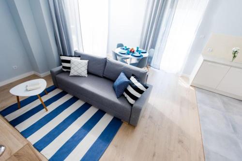 uma sala de estar com um sofá cinzento e um tapete azul e branco em Resort Apartamenty Klifowa Rewal 9 em Rewal