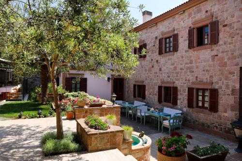 un patio con mesas y un árbol frente a un edificio en YundAntik Cunda Konaklari, en Ayvalık