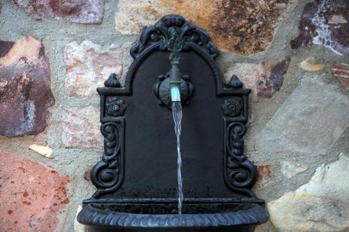 a black water fountain attached to a stone wall at YundAntik Cunda Konaklari in Ayvalık