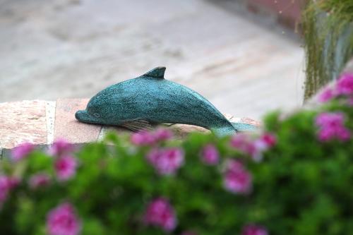 a statue of a dolphin sitting on a wall with flowers at YundAntik Cunda Konaklari in Ayvalık
