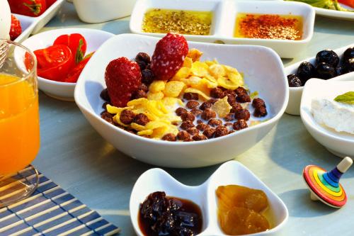 a table topped with bowls of cereal and fruit at YundAntik Cunda Konaklari in Ayvalık