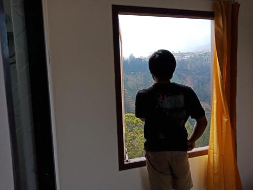 a young man looking out of a window at Bromo Backpacker Tosari in Pasuruan