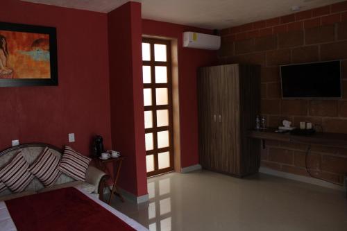 a bedroom with red walls and a bed and a television at Hotel Boutique La Herencia in Tequisquiapan