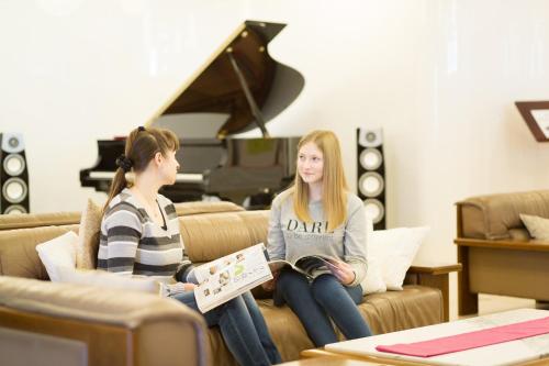 two girls sitting on a couch in front of a piano at Sakaide Plaza Hotel in Sakaide