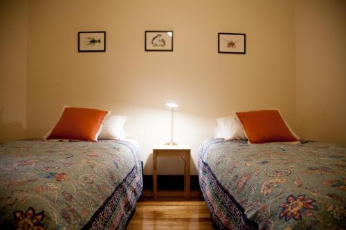een slaapkamer met 2 bedden en een tafel met een lamp bij The Pear Cottage in Nubeena