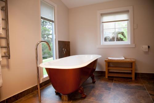 een badkamer met een bad en een raam bij The Pear Cottage in Nubeena