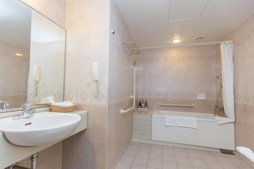 a white bathroom with a sink and a bath tub at Hotel Lake View Mito in Mito