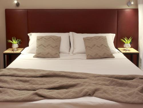 un letto con lenzuola e cuscini bianchi in una camera da letto di Hotel Aloisi a Lecce