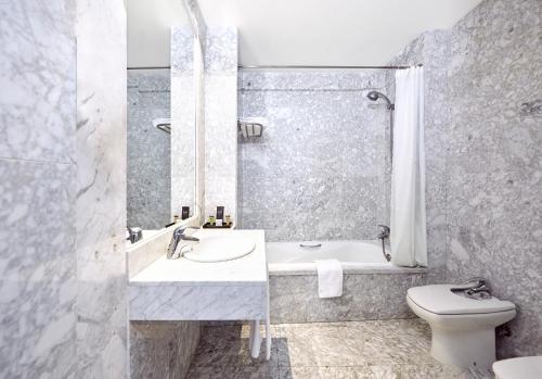 a bathroom with a sink and a tub and a toilet at Barceló León Conde Luna in León