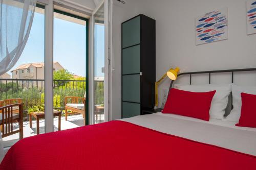 a bedroom with a red bed and a balcony at Apartments Sarbunal in Bol
