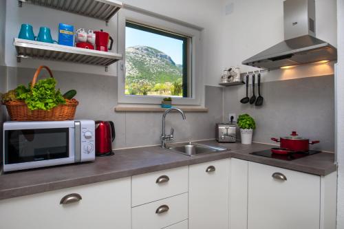 a kitchen with a microwave and a sink and a window at Apartments Sarbunal in Bol