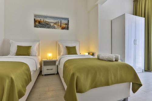 a bedroom with two beds with green sheets at Apart Hotel Sea Fort in Sutomore
