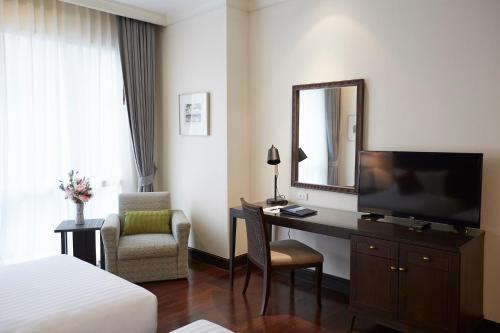 a hotel room with a bed and a desk with a television at The Rose Residence, Bangkok in Bangkok