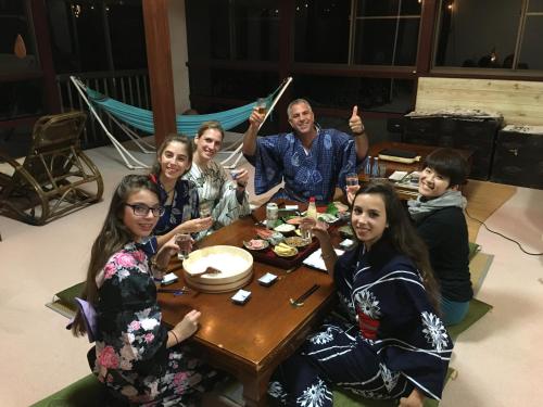 a group of people sitting around a table at わくわく自然体験の宿ゲストハウス山楽 in Itoigawa