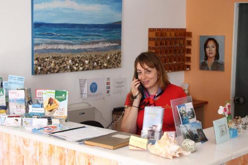 Una mujer sentada en una mesa hablando por celular en Annita's Village Hotel, en Agia Anna de Naxos