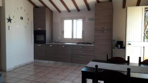 a kitchen with wooden cabinets and a table and a window at Casa di Caucana in Santa Croce Camerina