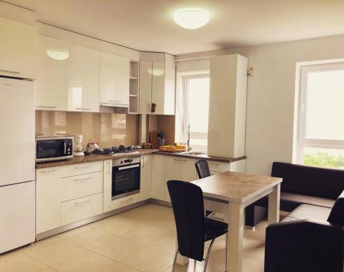 Una cocina con gabinetes blancos y una mesa con sillas. en Avantgarden Apart, en Brasov