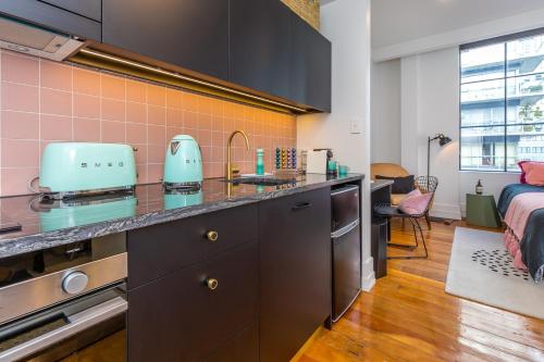 a kitchen with a counter top and a room with a bed at Deluxe Heritage - Roof Top Pool & Gym near Sky Tower in Auckland