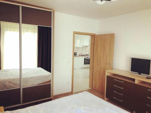 Un dormitorio con una cama y una cómoda con televisión. en Avantgarden Apart, en Brasov