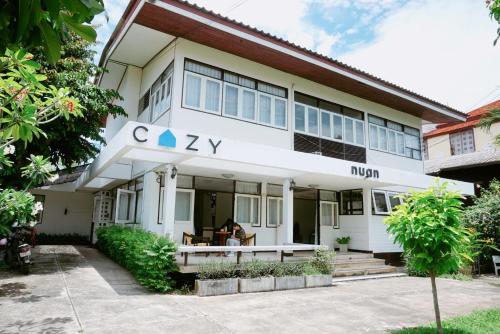 un edificio blanco con un cartel en la parte delantera en Cozy by Funwahn, en Chiang Mai