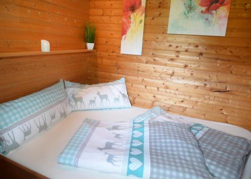 a bed in a wooden room with two pillows at Schwammerlhütte in Krispl