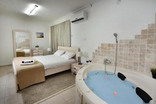 a bedroom with a bed and a tub in a room at אחוזת חוף כנרת kinneret village in Tiberias