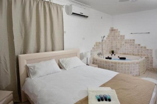 a bedroom with a white bed and a bath tub at אחוזת חוף כנרת kinneret village in Tiberias