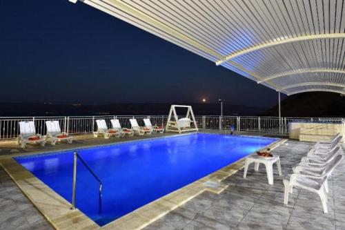 a large swimming pool with chairs and a roof at אחוזת חוף כנרת kinneret village in Tiberias