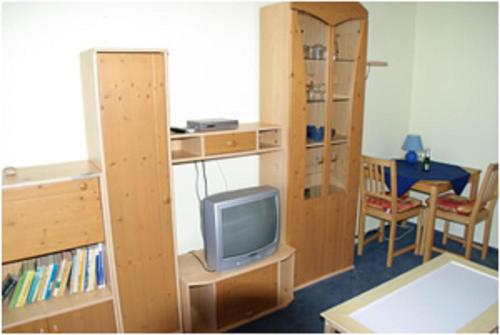 a room with a tv and a book shelf and a desk at Haus Nordlicht in Helgoland