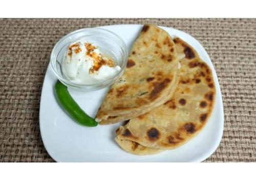 a white plate with a plate of food with dip and a green pepper at Valley View rooms near Khajjiar Lake in Lāhri