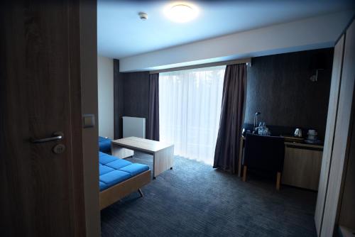 a hotel room with a blue couch and a desk at Hotel Jakuszyce Sport & Spa in Szklarska Poręba