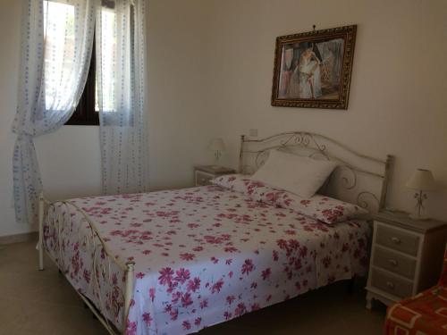 a bedroom with a bed with a floral bedspread at Le Fanciulle in Marina di Pescoluse